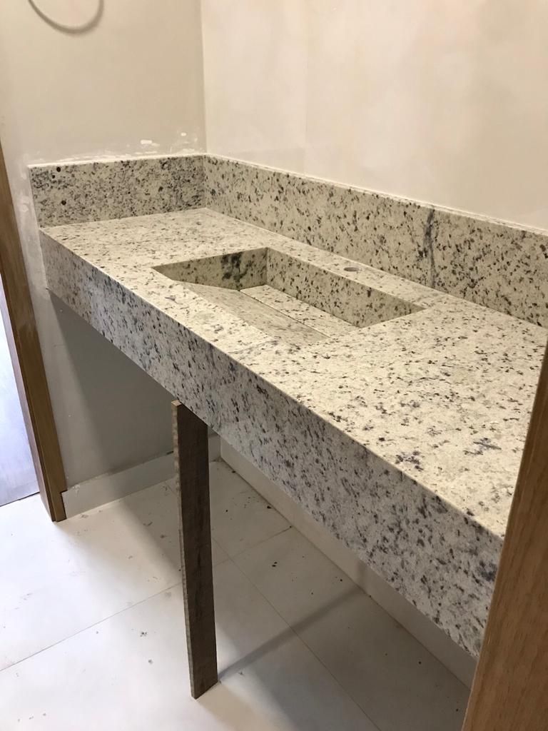 Bancada em granito branco com cuba esculpida na pedra.