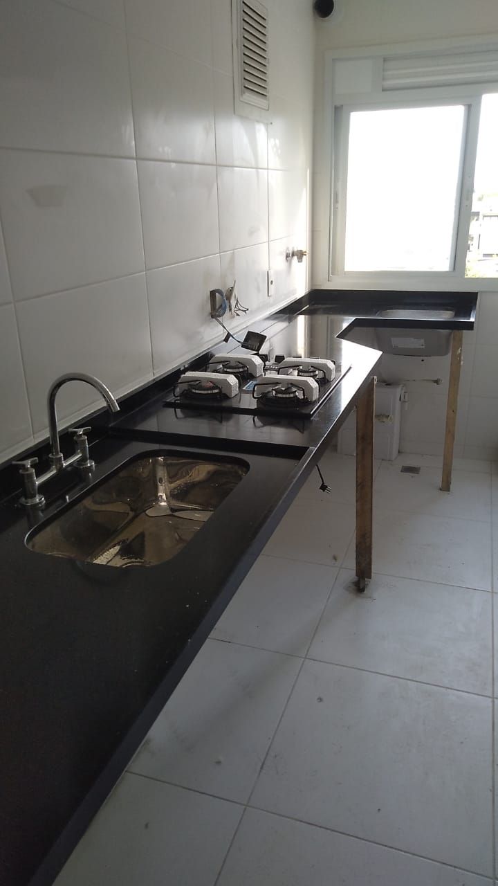 Bancada em L com cuba inox e frontão em granito preto.