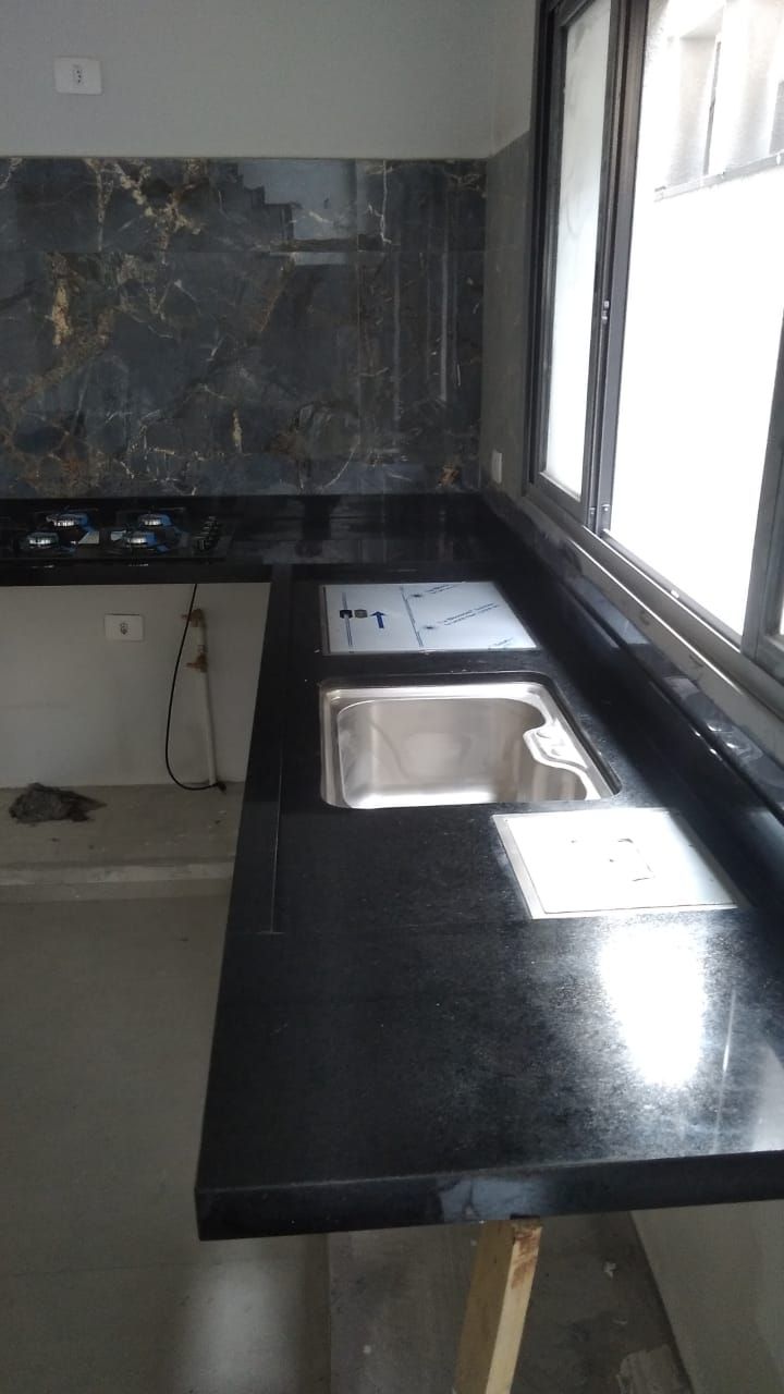 Bancada preta com painel em pedra exótica junto à janela.