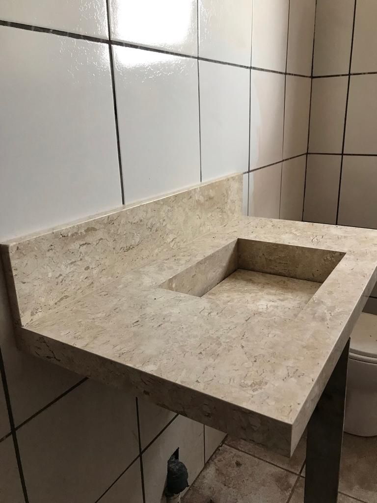 Bancada em travertino com cuba esculpida na pedra.